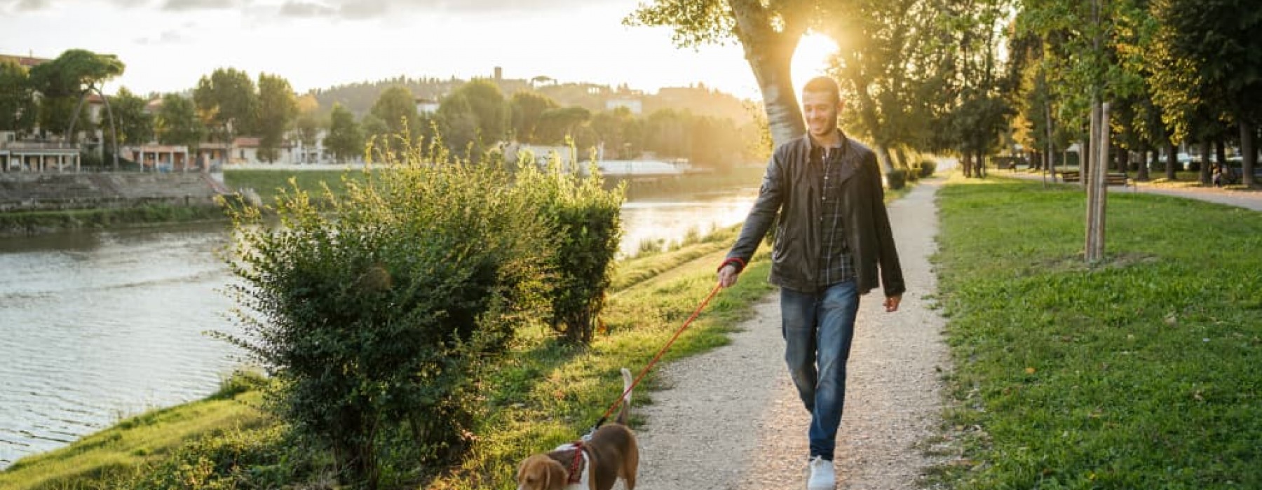 lifestyle image of a man walking beside greenery and a body of water