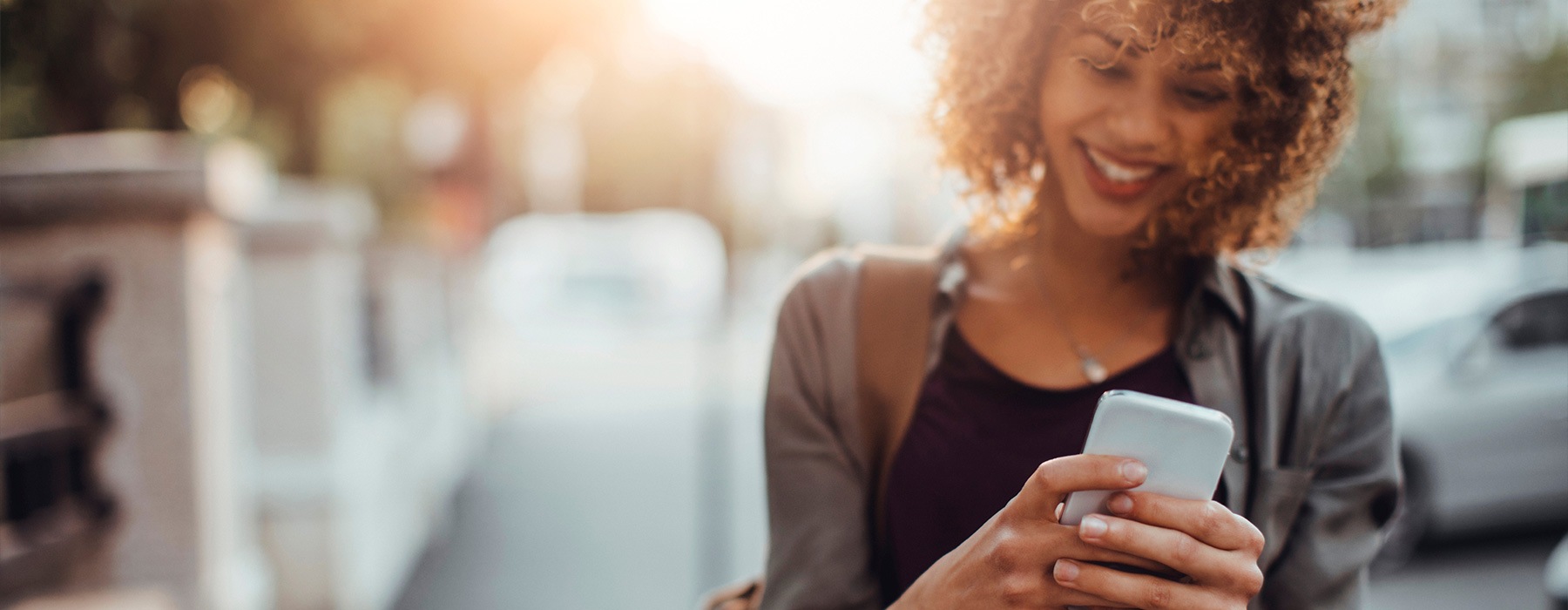 lifestyle image of a woman typing on her smart phone outdoors